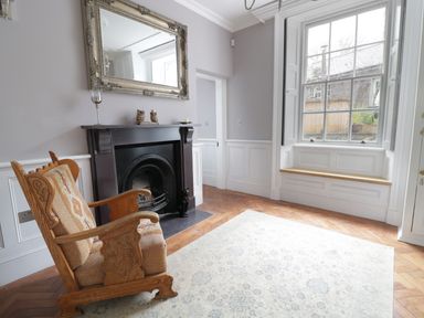 A room with an armchair by a fireplace and a large window with a wooden bench at Bryn Derwen Bethesda near Caernarfon