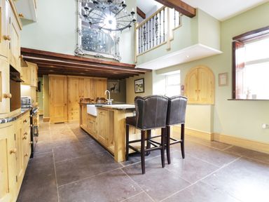 A kitchen with wooden cabinets a central island with a sink two chairs and a large mirror at Bryn Derwen Bethesda near Caernarfon