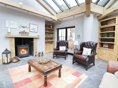 A sitting room with two leather armchairs a wood burning stove a wooden coffee table and skylight at Bryn Derwen Bethesda near Caernarfon
