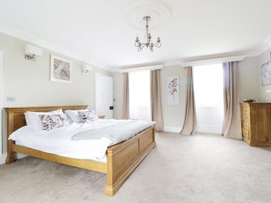 A bedroom with a wooden bed and dresser with beige curtains at Bryn Derwen in Bethesda near Caernarfon