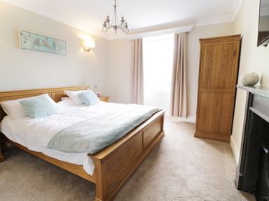 A bedroom with a wooden bed white bedding blue pillows and a wooden wardrobe at Bryn Derwen Bethesda near Caernarfon