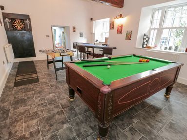 A game room with a pool table foosball table dartboard and bar stools at Bryn Derwen Bethesda near Caernarfon
