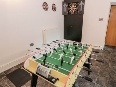 A game room with a foosball table and a dartboard on the wall at Bryn Derwen in Bethesda near Caernarfon