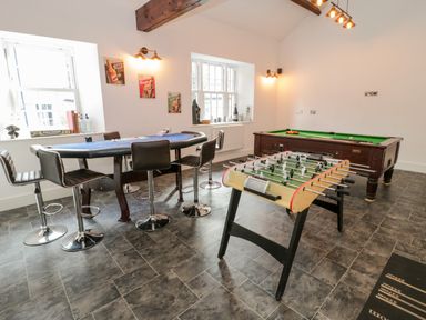 A game room with a poker table surrounded by chairs a foosball table and a pool table at Bryn Derwen Bethesda near Caernarfon