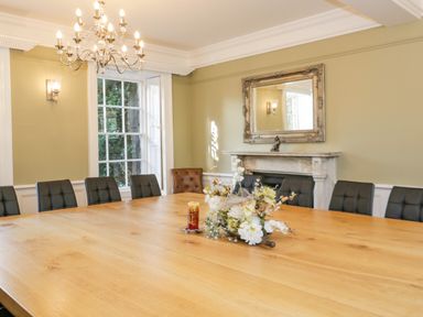 A dining room with a large wooden table surrounded by black chairs and a chimney with a mirror above at Bryn Derwen Bethesda near Caernarfon