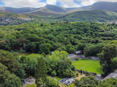 A landscape with dense trees a soccer field and seating area at Bryn Derwen in Bethesda near Caernarfon