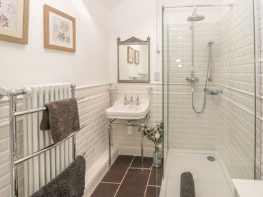 A bathroom with a glass-enclosed shower a white sink and a chrome towel rack with towels at Bryn Derwen Coach House Bethesda