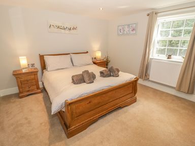 A bedroom with a wooden bed and two bedside tables with lamps at Bryn Derwen Coach House in Bethesda