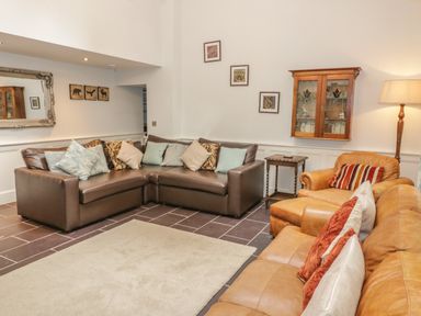 A living room with brown leather and tan leather sofas with cushions and a floor lamp at Bryn Derwen Coach House in Bethesda