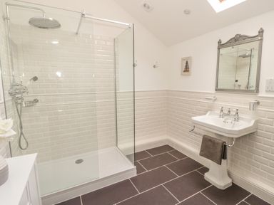 A bathroom with a walk in shower and a pedestal sink with a mirror at Bryn Derwen Coach House Bethesda