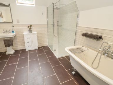 A bathroom with a clawfoot bathtub a glass shower enclosure a pedestal sink and a small white cabinet at Bryn Derwen Coach House in Bethesda
