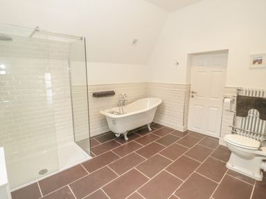 A bathroom with a walk in shower a clawfoot bathtub and a toilet at Bryn Derwen Coach House in Bethesda