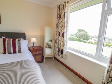A bedroom with a bed pillow bedside table lamp full length mirror and window at Bryn Coch Bach in Dyffryn Ardudwy