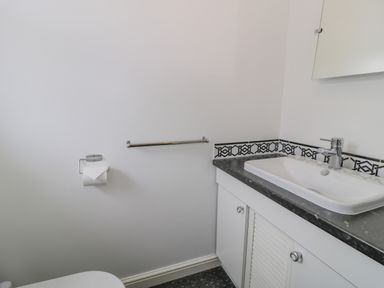 A bathroom with a sink countertop and toilet paper holder at Bryn Coch Bach in Dyffryn Ardudwy