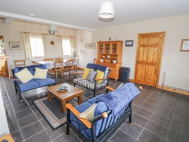 A living room with blue sofas a wooden coffee table a dining table and chairs and a wooden cabinet at 8 Lios Na Sioga in Binghamstown near Belmullet County Mayo