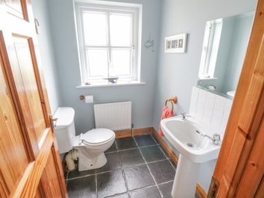 A bathroom with a toilet and a sink under a window at 8 Lios Na Sioga in Binghamstown near Belmullet County Mayo