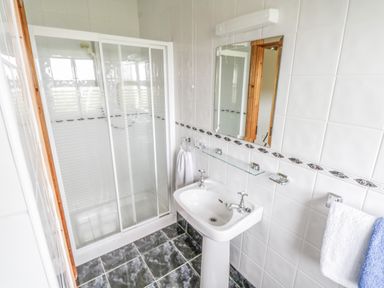 A bathroom with a shower enclosure a sink mirror and towels at 8 Lios Na Sioga Binghamstown near Belmullet County Mayo