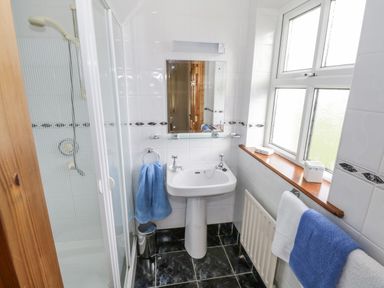 A bathroom with a pedestal sink mirror shower enclosure blue and white towels at 8 Lios Na Sioga Binghamstown near Belmullet County Mayo
