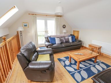 A living room with leather sofas and a wooden coffee table on a blue rug at 8 Lios Na Sioga in Binghamstown near Belmullet County Mayo