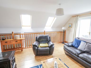 A living room with leather armchair and sofa wooden table and railing and skylights at 8 Lios Na Sioga in Binghamstown near Belmullet County Mayo