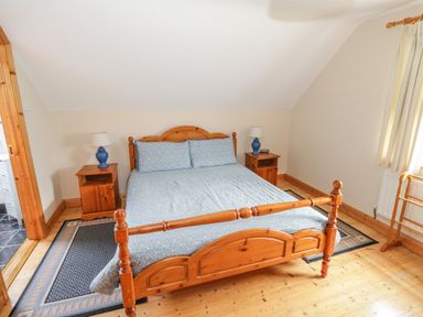 A bedroom with a wooden double bed flanked by two wooden nightstands with lamps at 8 Lios Na Sioga Binghamstown near Belmullet County Mayo