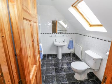 A bathroom with a toilet sink mirror skylight and wooden door at 8 Lios Na Sioga in Binghamstown near Belmullet County Mayo