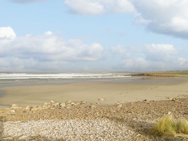 A beach with sand and pebbles with waves and clouds at 8 Lios Na Sioga in Binghamstown near Belmullet County Mayo