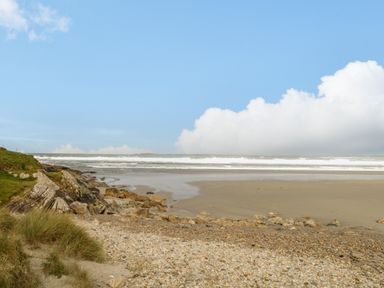 A sandy beach with rocks and grass near the shore at 8 Lios Na Sioga in Binghamstown near Belmullet County Mayo