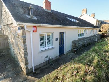 Exterior of a single-story house with a blue door stone wall and grassy area at Llety'r Llwynog Llanfallteg near Narberth