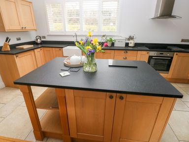 A kitchen with wooden cabinets a black countertop and a vase of flowers on an island at Llety'r Llwynog in Llanfallteg near Narberth