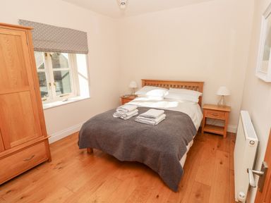A bedroom with a wooden bed and bedside tables and a wooden wardrobe at Llety'r Llwynog in Llanfallteg near Narberth