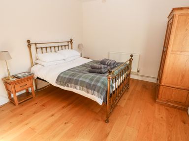 A bedroom with a metal bed frame wooden nightstands lamps and a wooden wardrobe at Llety'r Llwynog in Llanfallteg near Narberth