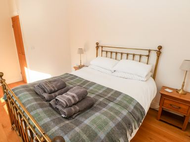 A bedroom with a brass bed frame two bedside tables with lamps and folded towels on the bed at Llety'r Llwynog in Llanfallteg near Narberth