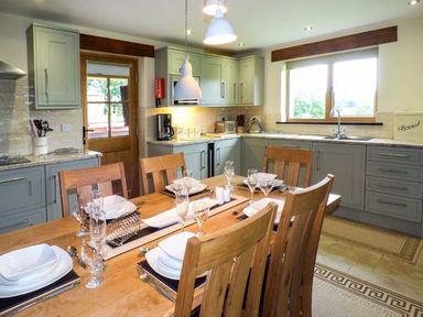 A kitchen with wooden dining table set for six and cabinets with appliances at Tyn Y Celyn Uchaf Clocaenog near Ruthin