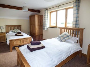 A bedroom with two single beds pillows towels wooden wardrobe and window at Tyn Y Celyn Uchaf in Clocaenog near Ruthin