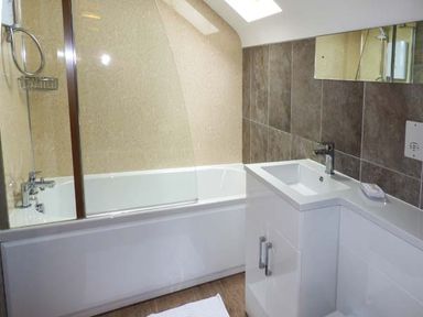 A bathroom with a bathtub shower combination and a sink with a cabinet at Tyn Y Celyn Uchaf in Clocaenog near Ruthin