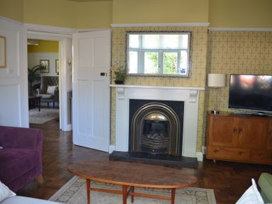 A living room with a fireplace mirror television wooden cabinet and coffee table at Lily House in Minehead