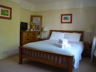 A bedroom with a wooden bed with folded towels on it and wooden furniture at Lily House in Minehead