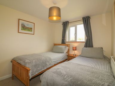 A bedroom with two single beds a bedside table with a lamp and a window with curtains at Higher Whiddon Farm Whiddon Well Ashburton near Newton Abbot