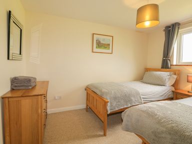 A bedroom with two single beds a bedside table a chest of drawers and a window at Higher Whiddon Farm Whiddon Well in Ashburton near Newton Abbot