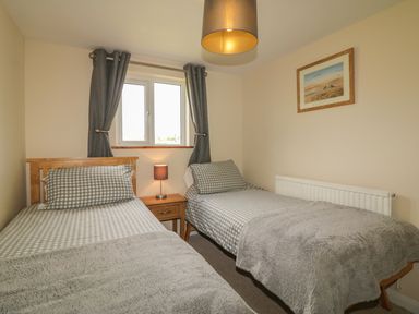 A bedroom with two single beds a bedside table a lamp and a window with curtains at Higher Whiddon Farm Whiddon Well Ashburton near Newton Abbot