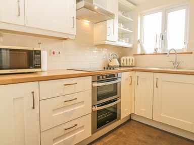 A kitchen with white cabinets wooden countertops a microwave oven stove kettle toaster sink and window at Higher Whiddon Farm Whiddon Well Ashburton near Newton Abbot
