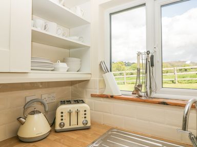 A kitchen corner with a kettle toaster knives and utensils near a window with a view at Higher Whiddon Farm Whiddon Well Ashburton near Newton Abbot