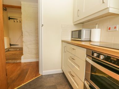 A kitchen with white cabinets wooden countertop microwave paper towel holder and built in oven at Higher Whiddon Farm Whiddon Well Ashburton near Newton Abbot