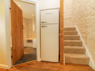 A staircase with carpet next to a white Montpellier fridge and an open door leading to a tiled bathroom at Higher Whiddon Farm Whiddon Well Ashburton near Newton Abbot
