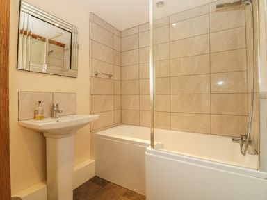 A bathroom with a pedestal sink a mirror above and a bathtub with a glass shower screen at Higher Whiddon Farm Whiddon Well Ashburton near Newton Abbot