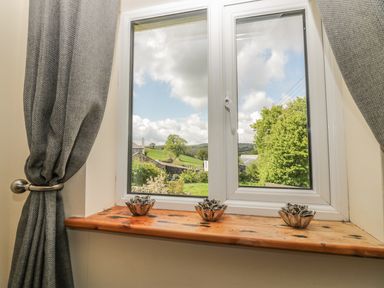 A window with three decorative holders on the wooden sill and grey curtains at Higher Whiddon Farm Whiddon Well Ashburton near Newton Abbot