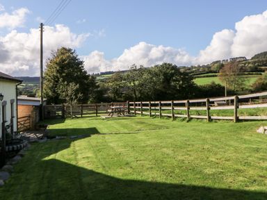 A fenced garden area with a picnic table and grassy lawn at Higher Whiddon Farm Whiddon Well Ashburton near Newton Abbot