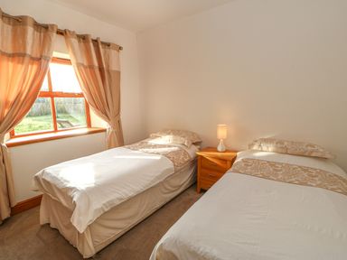 A bedroom with two single beds and a wooden nightstand with a lamp between them at Swift Cottage Milton near Brampton