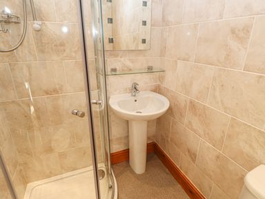 A bathroom with a shower enclosure sink and mirror at Swift Cottage in Milton near Brampton